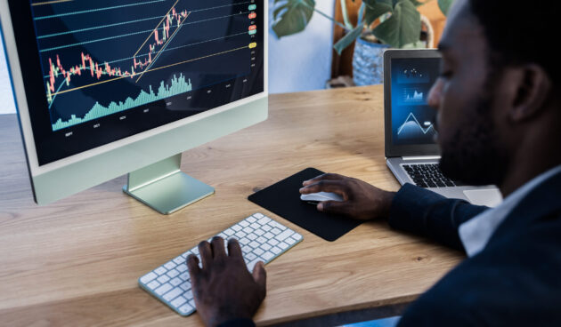 African trader studying stock market at home - Focus on computer screen