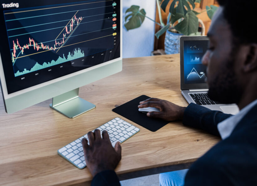 African trader studying stock market at home - Focus on computer screen